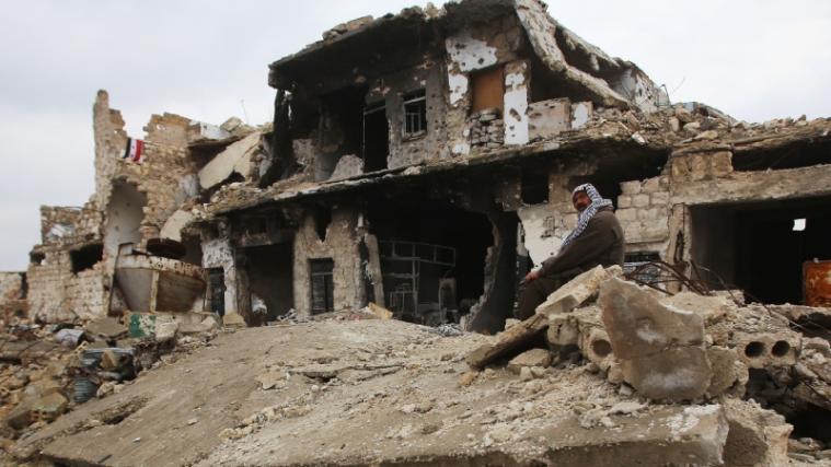 Ein Mann sitzt vor den Resten seines zerbombten Hauses in Aleppo.