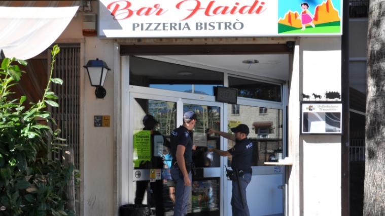 Zwei Polizeibeamten befestigen die Schließungsverordnung an der Tür der Bar "Haidi". - Foto: Quästur