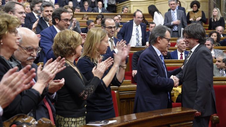 Der neugewählte Regierungschef Kataloniens, Carles Puigdemont (ganz rechts), bekommt die Glückwünsche seines Vorgängers Artur Mas und den Beifall der Parlamentarier.