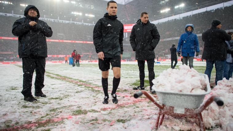 Schiedsrichter Robert Kampka geht vor dem Spiel an einer Schubkarre mit Schnee vorbei.