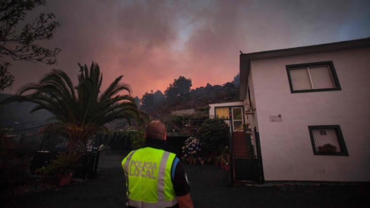 Ein Polizist beobachtet besorgt am Ortsrand von El Paso den auf der Insel La Palma wütenden Waldbrand.