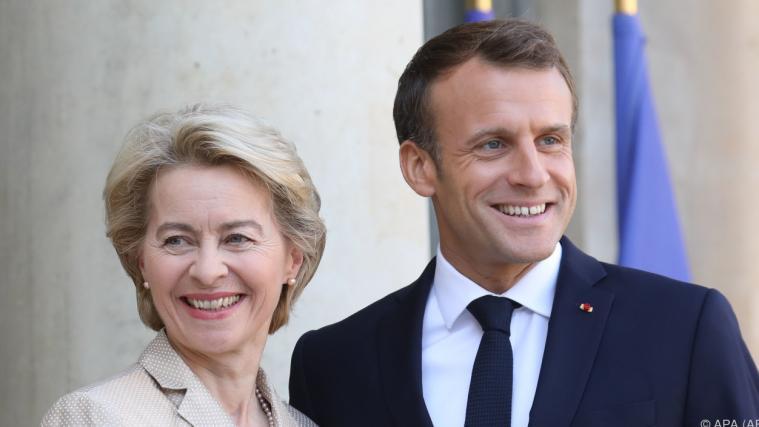 Macron und von der Leyen lachen in die Kamera.