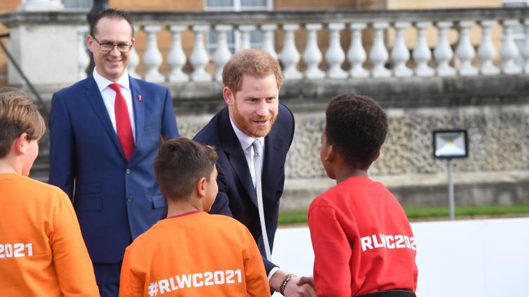 Harry unterhält sich mit Kindern, die im Garten des Palastes Rugby spielen durften.