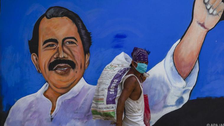 Mann mit Maske in Managua vor einem Bild von Präsident Ortega.