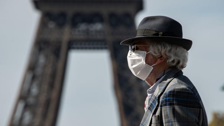 Mann mit Schutzmaske in Paris. Im Hintergrund der Eifelturm.