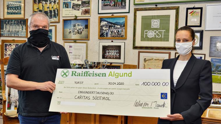 Cellina von Mannstein der Brauerei FORST übergibt den Scheck von 100.000 Euro an den Direktor der Caritas Südtirol Paolo Valente.