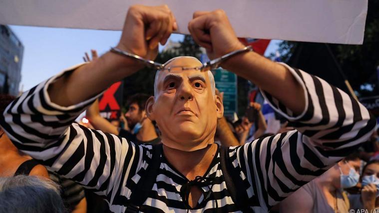 Demonstrant mit Netanyahu-Maske sieht Premier reif für Handschellen.