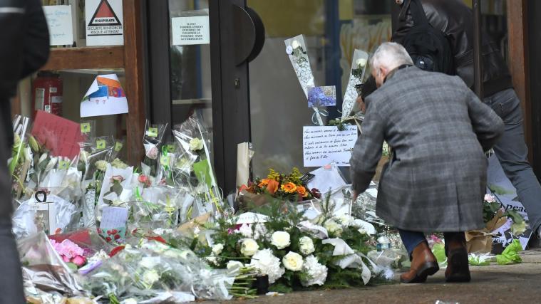 Menschen legen Blumen an den Eingang der Mittelschule, wo das Opfer unterrichtet hat.