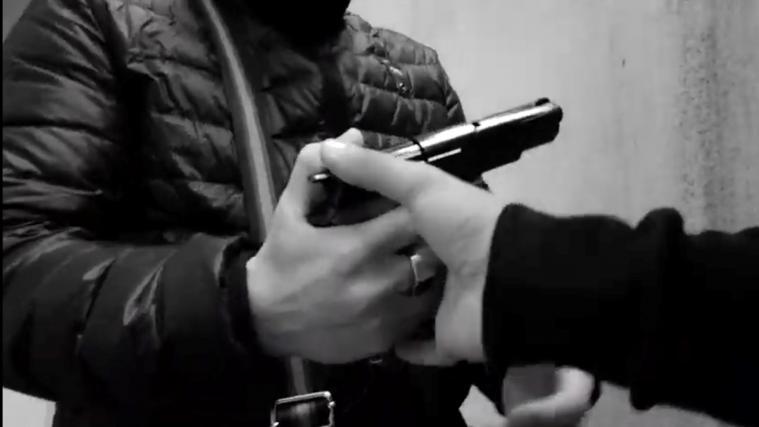 Ein Ausschnitt aus dem Rappervideo, in dem eine Waffe – wahrscheinlich eine Spielzeugwaffe – den Besitzer wechselt.