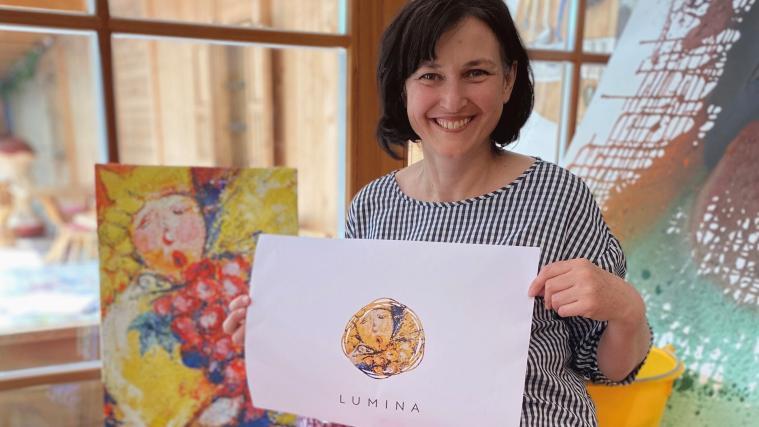 Der „Weinengel“ der Lüsner Künstlerin Ulrike Silgoner (im Hintergrund das Originalbild) wurde als Etikette für die Lumina-Flaschen, die ab Juli zugunsten von Südtirol hilft verkauft werden, gewählt.